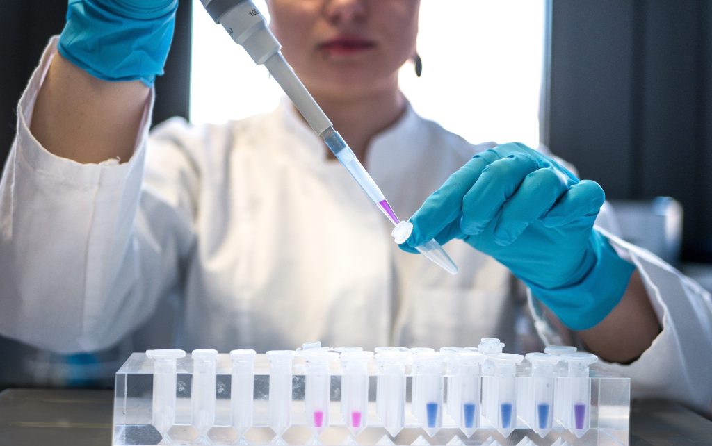 Image of a scientist pipetting a liquid into a vial