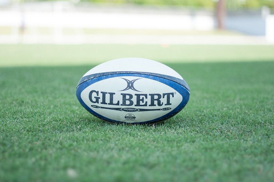 A gilbert rugby ball on a green pitch